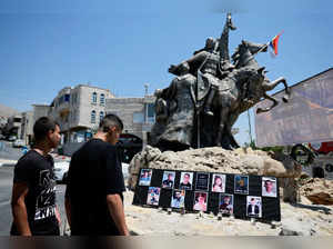 Young people look at the pictures of children and teens killed at a soccer pitch by a rocket Israel says was fired from Lebanon, at a roundabout in Majdal Shams