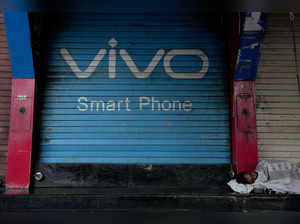 A man sleeps outside a closed shop shutter painted with an advertisement for Vivo smart phone at a market area in India's financial capital Mumbai