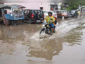 Gurugram: A man rides a bike on a flooded road after rain, in Gurugram. (PTI Pho...