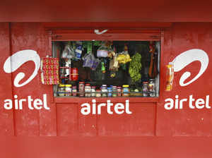 A vendor waits for customers at his grocery shop, painted with an advertisement for Bharti Airtel, in Kochi