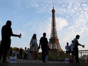 People offer bottles of water for sale as the Eiffel Tower is seen in the background