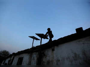 FILE PHOTO: A boy dusts off a solar panel installed on the rooftop of his house on the outskirts of Ahmedabad