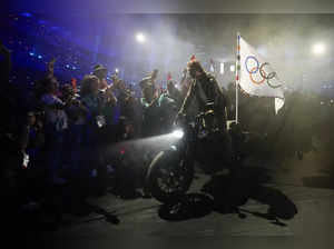 Tom Cruise rides a motorbike with the Olympic flag attached during the 2024 Summ...