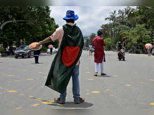 A student wearing a Bangladesh flag controls traffic on a road in the absence of traffic police after days of unrest in Dhaka