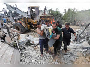 Palestinians walk at the site of an Israeli airstrike, in central Gaza Strip