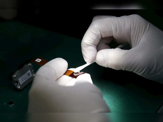 FILE PHOTO: A worker of Ayala Corp's Integrated Micro-Electronics Inc. (IMI) wipes an automotive computer component part at an electronics assembly line in Binan, Laguna