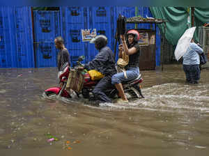 Kolkata: Commuters move through a waterlogged road during rain, in Kolkata. (PTI...