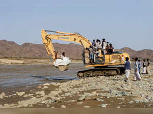 Aid and people are transported on an excavator following devastating floods, in Port Sudan