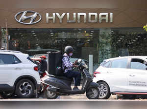 FILE PHOTO: A man rides a scooter past a Hyundai automobile showroom in Mumbai