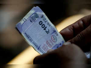 FILE PHOTO: A customer holds hundred rupees Indian currency notes near a roadside currency exchange stall in New Delhi