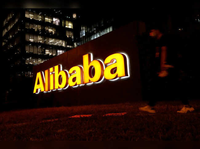 FILE PHOTO: Man walks past a logo of Alibaba Group at its office building in Beijing