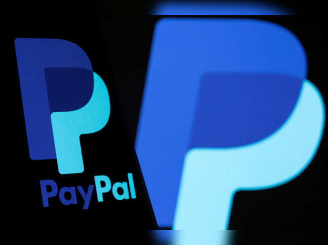 The PayPal logo is seen on a smartphone in front of the same logo displayed in this illustration