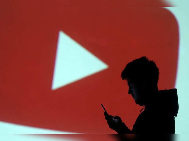 A silhouette of a mobile user is seen next to a screen projection of Youtube logo in this picture illustration