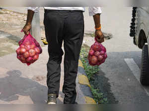 New Delhi: A man carries onions after purchasing from a shop as NCCF (National C...