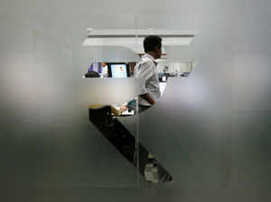 FILE PHOTO: FILE PHOTO: A currency trader is pictured through the symbol for the Indian Rupee on the floor of a trading firm in Mumbai