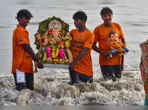 Mumbai: Devotees carry Ganpati idols for immersion at Girgaon Chowpatty, in Mumb...