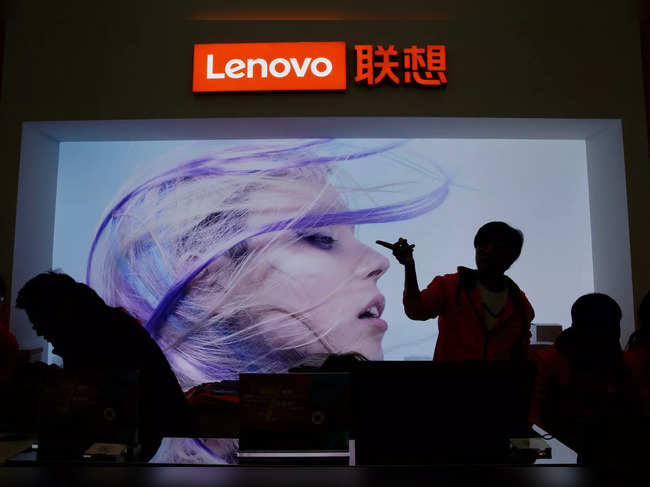 FILE PHOTO: An employee gestures next to a Lenovo logo at Lenovo Tech World in Beijing