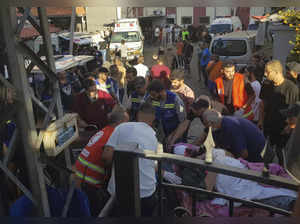 Civil Defense first-responders carry a man who was wounded after his handheld pa...