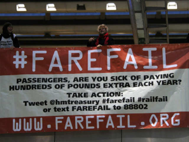 Protesters hold a banner calling for lower rail fares