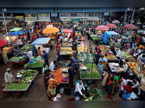 Customers buy fruits and vegetables at an open air evening market in Ahmedabad