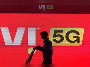 FILE PHOTO: A man walks across the LED display board showing the logo of Vodafone-Idea at the ongoing India Mobile Congress 2022, at Pragati Maidan, in New Delhi