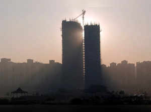 FILE PHOTO: Sun rays beam through two under construction residential buildings in Noida