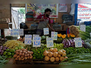 A vendor cleans his vegetables stall as he waits for customers at a fruit and vegetable market in Colombo