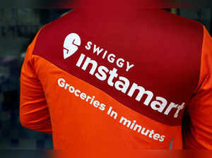 FILE PHOTO: A gig worker waits to pick an order outside a Swiggy's grocery warehouse, in New Delhi