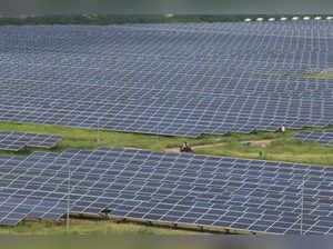 A man rides a motorcycle along the solar panels in Gujarat Solar Park also called Charanka Solar Park at Patan district in Gujarat