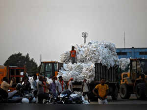 Workers stand near a parked truck loaded with empty plastic bags at the Deendayal Port in Kandla