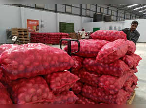 A worker of a retail chain pushes a trolley loaded with onion bags at Manchar village in Pune