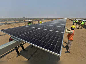 FILE PHOTO: Workers install solar panels at the Khavda Renewable Energy Park of Adani Green Energy Ltd (AGEL)  in Khavda