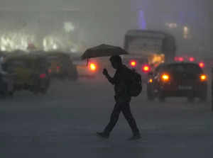 Kolkata: A pedestrian crosses a road amid rains in Kolkata, West Bengal. (PTI Ph...