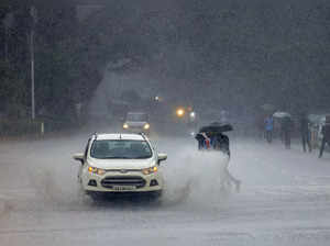 Bengaluru: Cricket fans cross a road near the M Chinnaswamy Stadium during rain ...