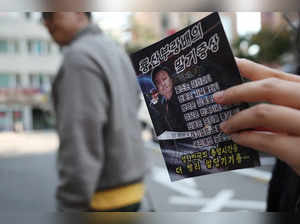 A woman looks at a North Korean propaganda leaflet denouncing South Korean President Yoon Suk Yeol and his wife Kim Keon Hee, apparently carried by balloons sent from North Korea, near the Presidential Office in Seoul