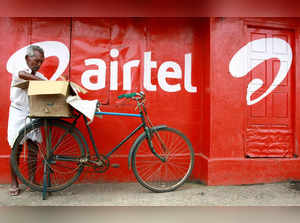 FILE PHOTO: FILE PHOTO: A man stands next to the wall of a grocery shop painted with an advertisement for Bharti Airtel in Kochi