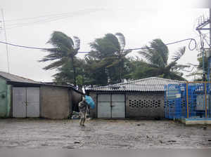 A man shields himself with his umbrella against strong winds and rain on the coa...