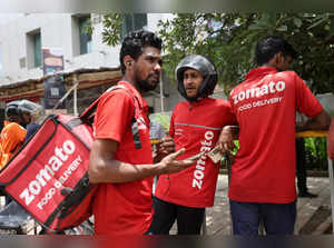 Gig workers wait in line to collect their delivery order outside a mall in Mumbai