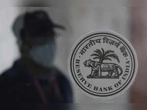 FILE PHOTO: A man walks behind the Reserve Bank of India (RBI) logo inside its headquarters in Mumbai