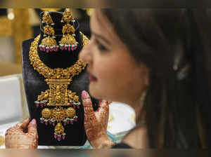 New Delhi: A woman checks gold ornaments at a jewellery showroom on the Dhantera...