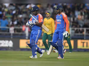 India's Sanju Samson, left, and his batting partner Tilak Varma walk between the...