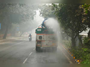 A vehicle sprays water to curb dust and pollution as the sky is enveloped with smog after Delhi's air quality turned "hazardous", in New Delhi