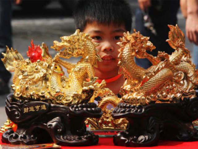 A boy looks at a pair of dragon sculptures