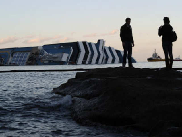 People take pictures in front of the cruise liner Costa Concordia