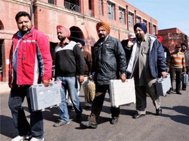 Poll officials carry EVMs as they leave for a polling station