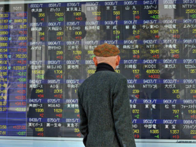 Man looks at an electronic board displaying Nikkei 225 index