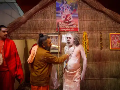 A Naga Sadhu stands as ash is applied on him before taking a holy dip for the first Shahi Snan