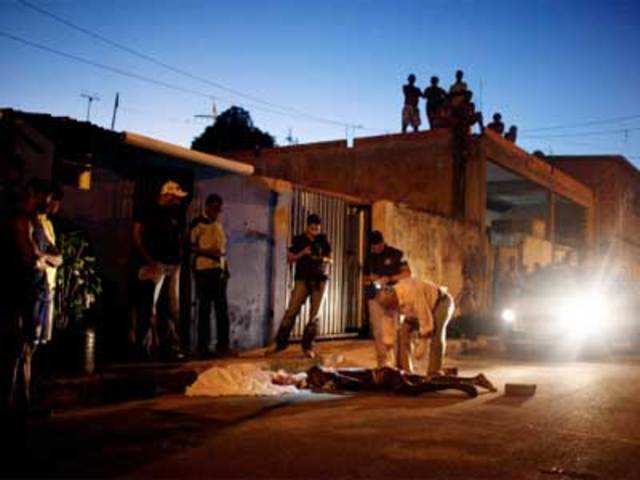 Police officers inspect the body of a man killed