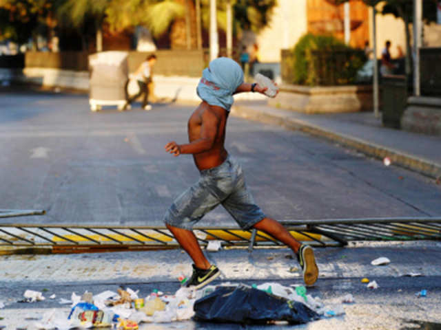 A protester throws a stone at riot policemen in Santiago