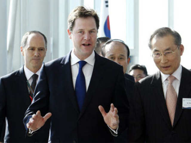 Nick Clegg gestures as he walks with officials